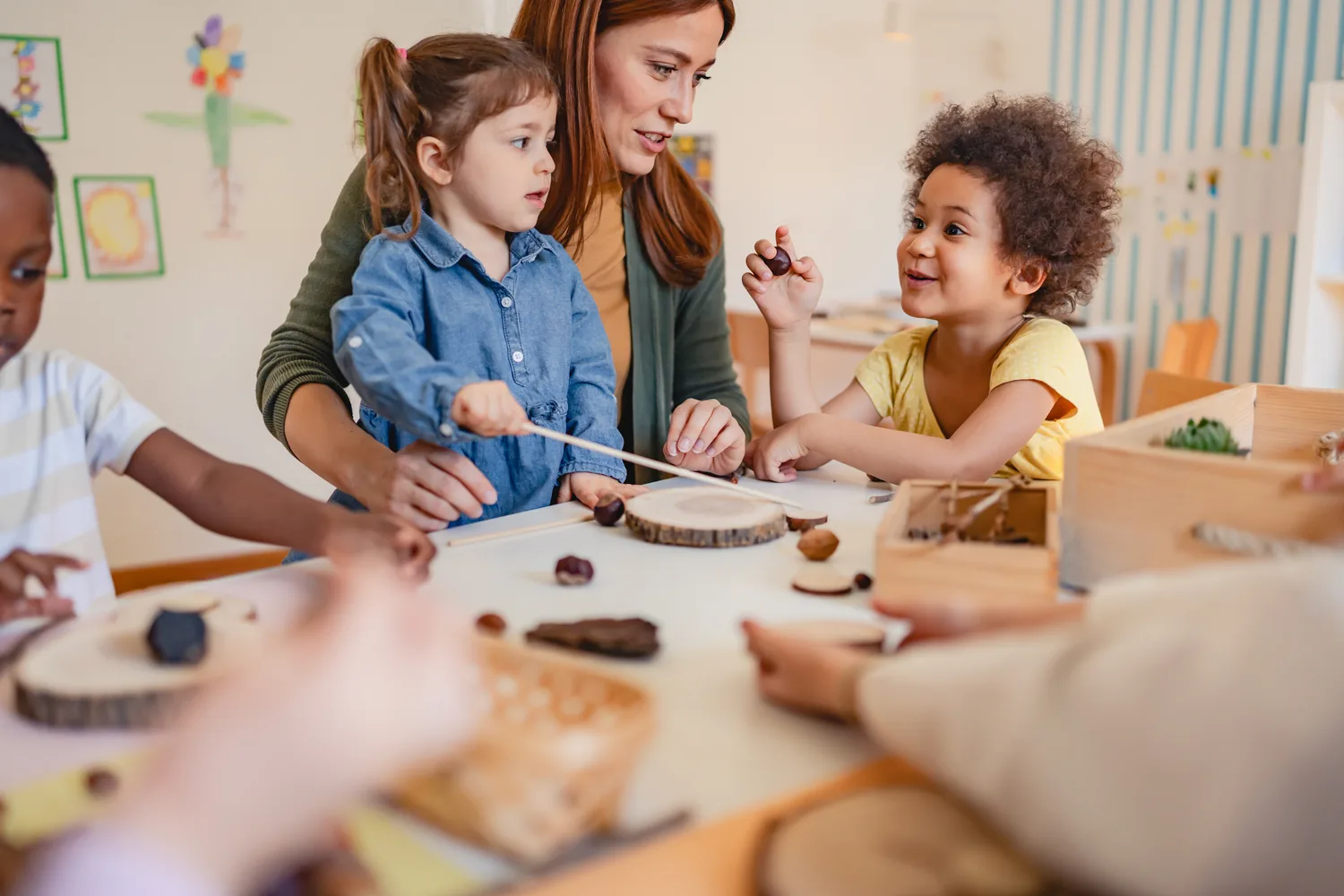 An educator and two children working with natural materials at a table