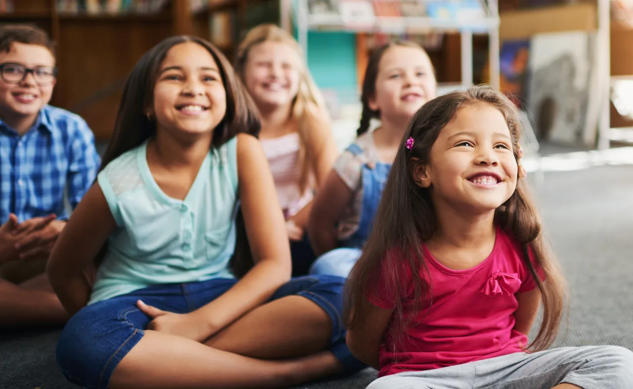 Smiling children sitting together on a classroom carpet