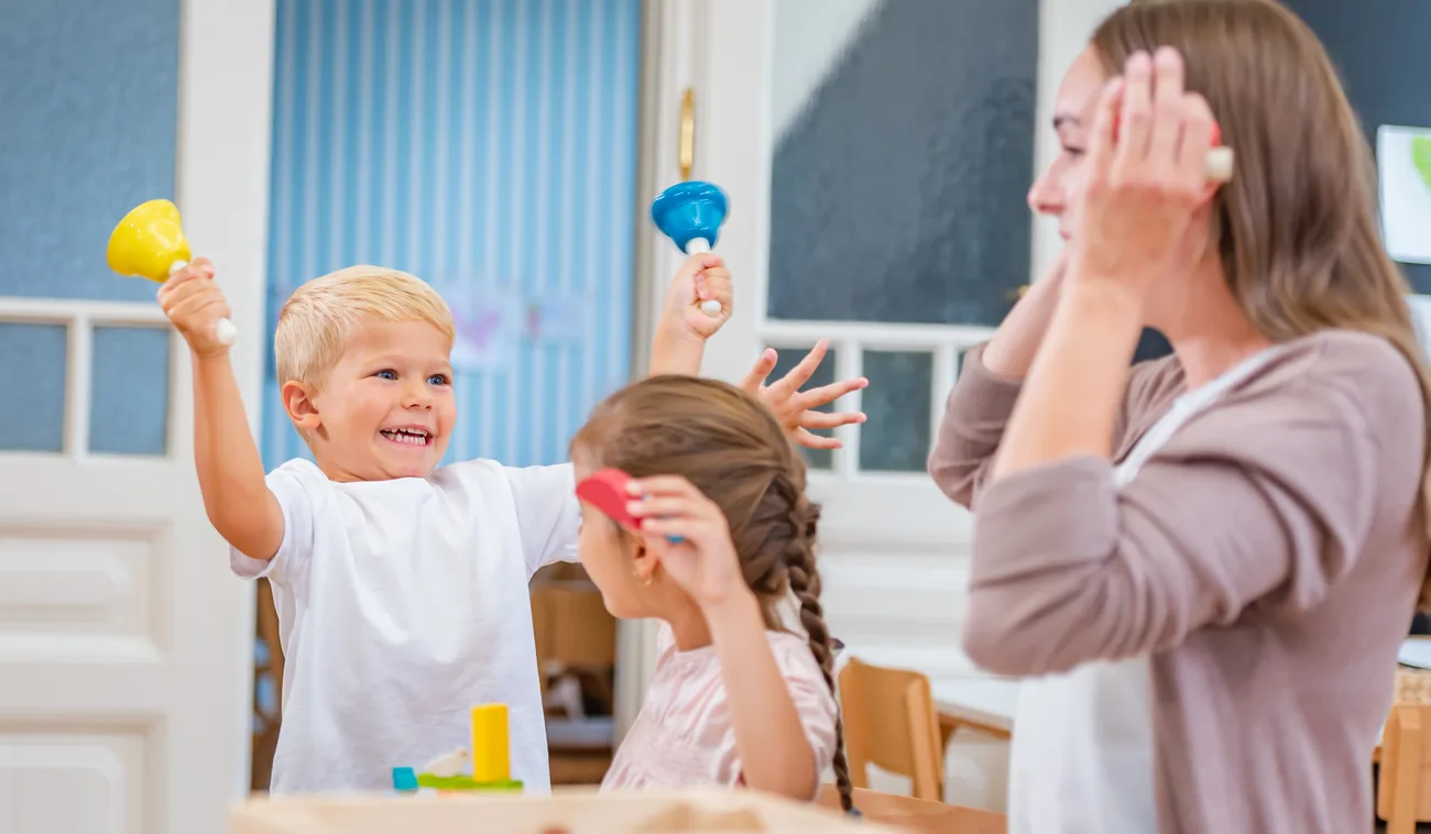 An educator leading a group of toddlers with colourful shakers