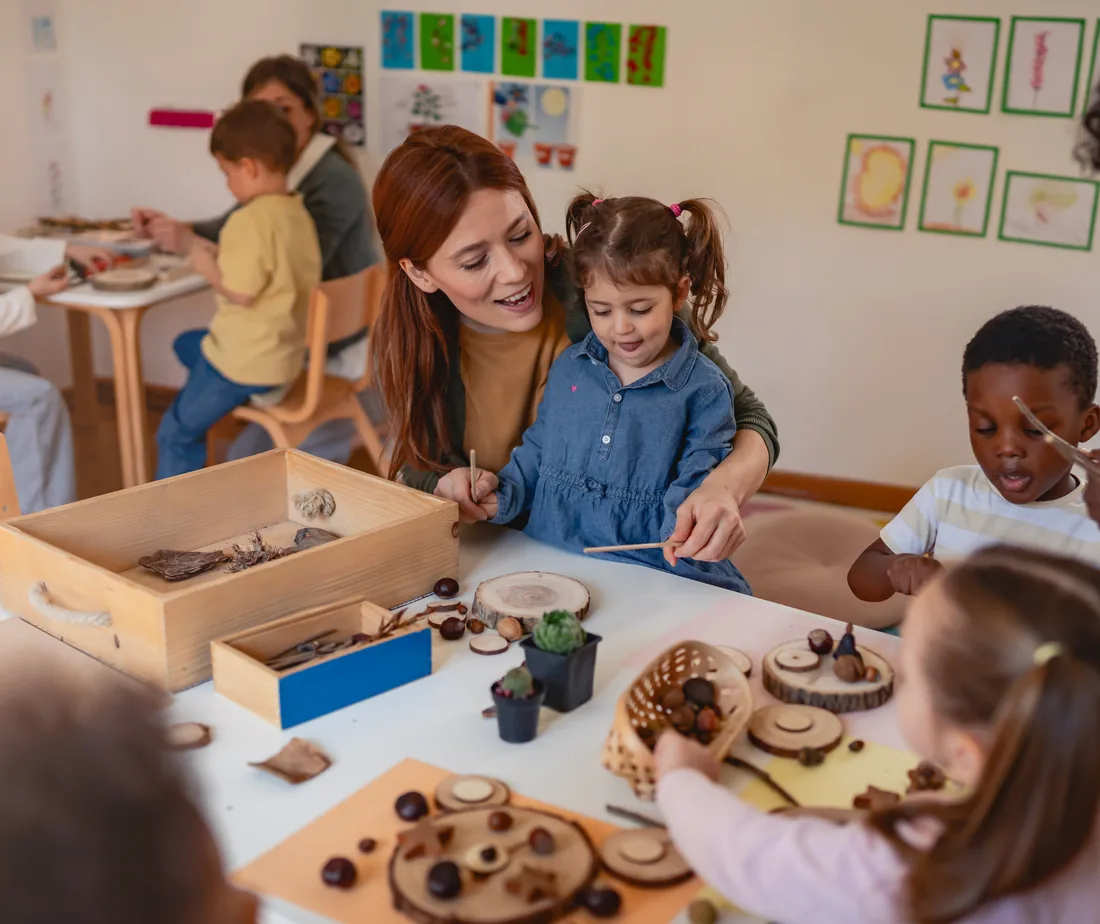 An educator and children sorting natural materials in wooden trays
