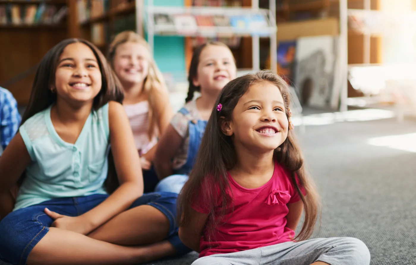 Smiling preschoolers sitting together on a classroom rug