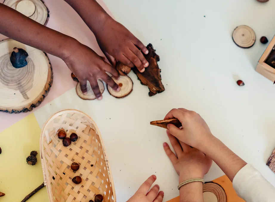 Children's hands arranging wood slices and loose parts